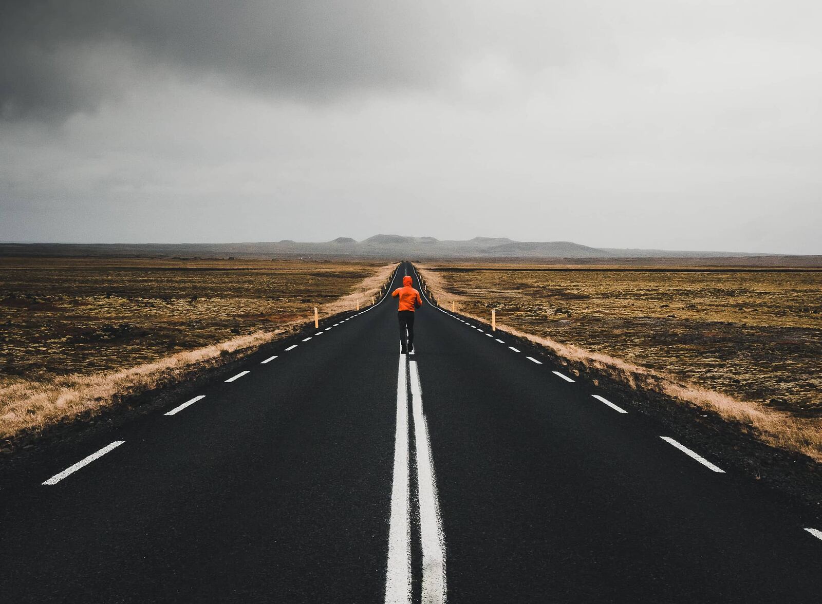 A lone runner on a long straight road through open country